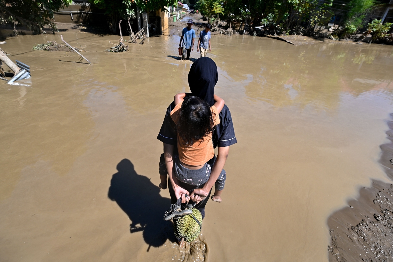 People walk through a flooded area in Meureudu, Pidie Jaya district in Indonesia's Aceh province on Sunday. (Yonhap-AFP)