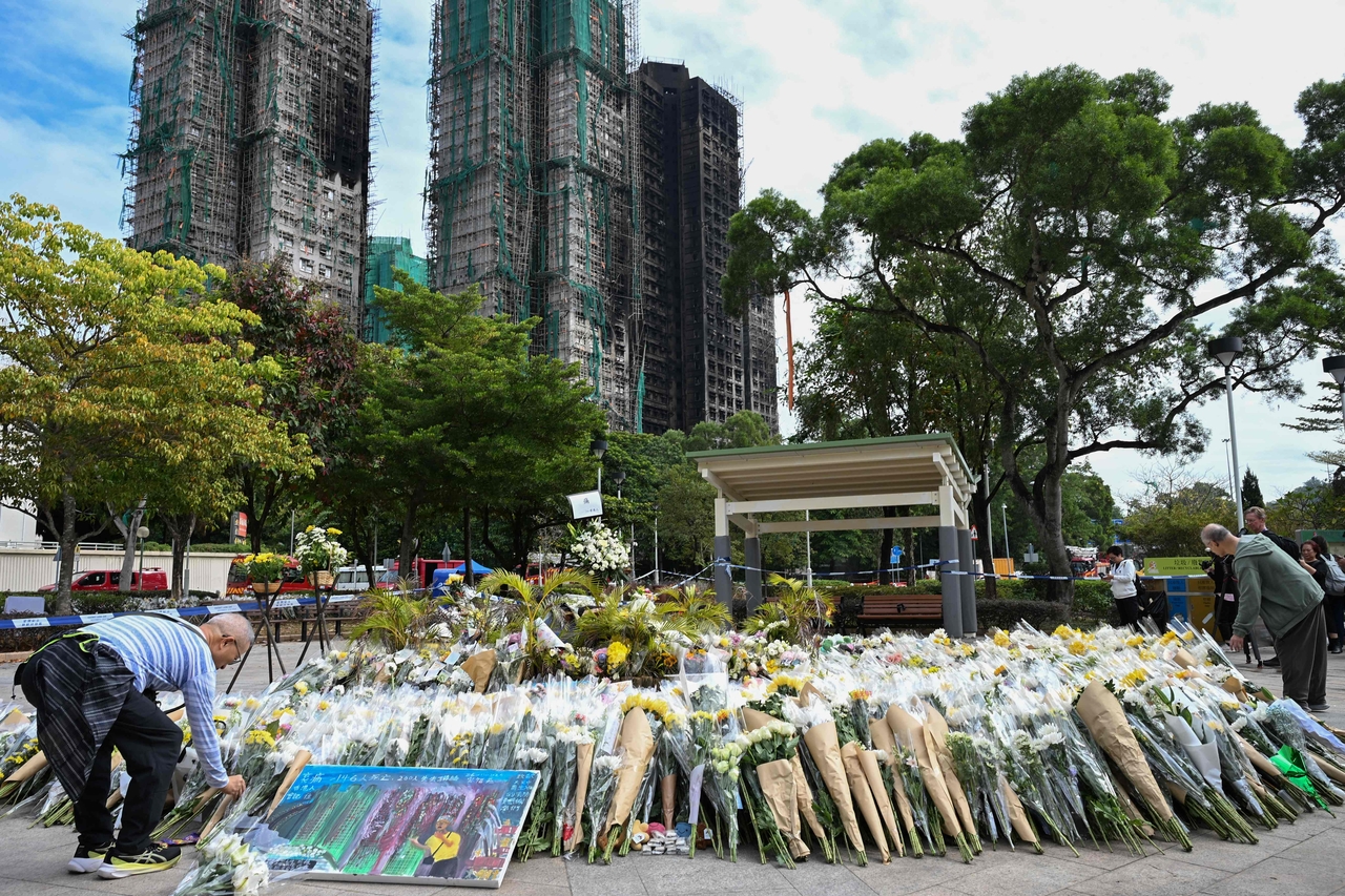 Mourners lay flowers as they pay their respects for victims at a makeshift memorial outside the Wang Fuk Court apartment blocks in the aftermath of the deadly November 26 fire in Hong Kong's Tai Po district on Monday. (AFP-Yonhap)