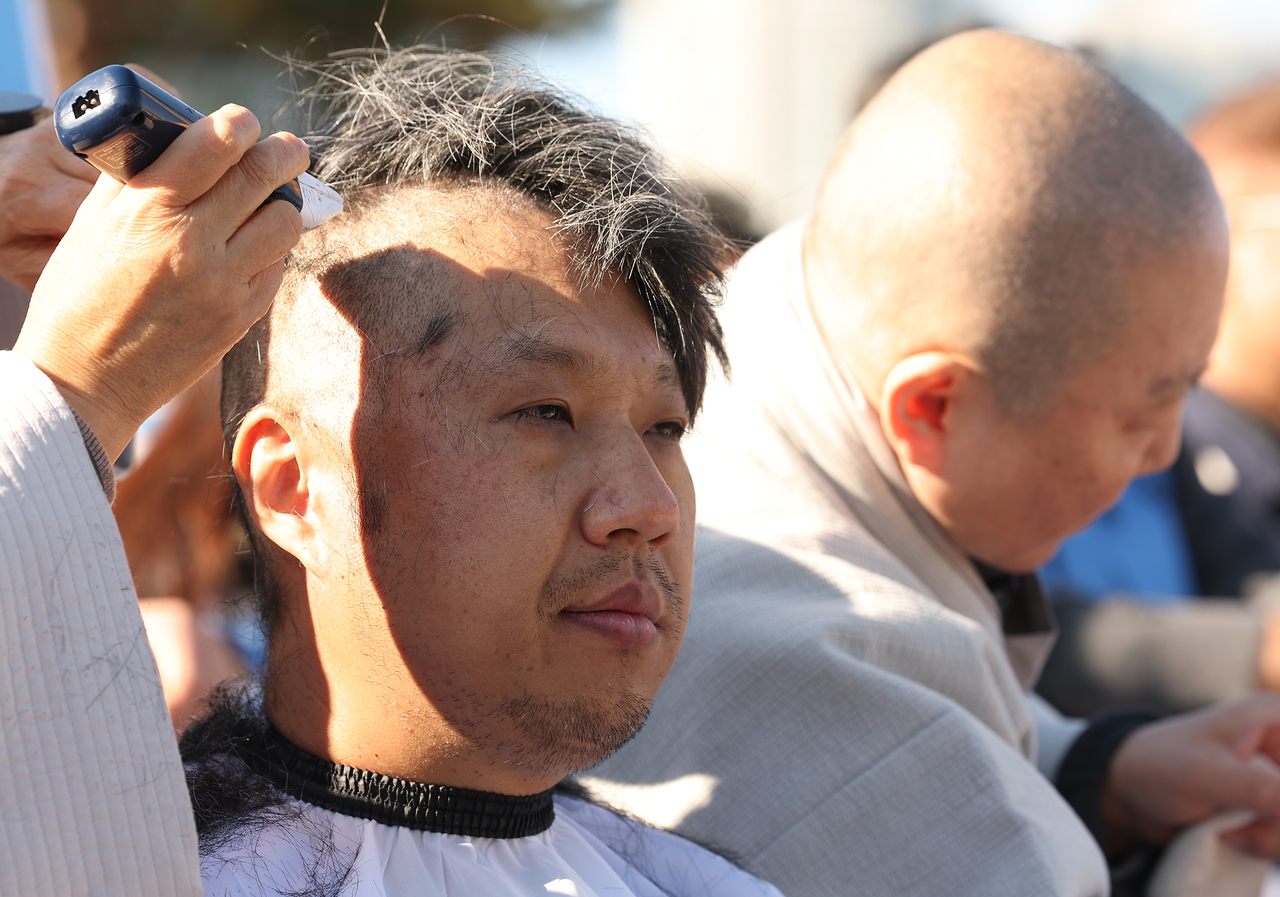 Relatives of the victims of the Jeju Air crash in December 2024 shave their heads as they begin an indefinite sit-in in front of the presidential office on Monday. (Yonhap)