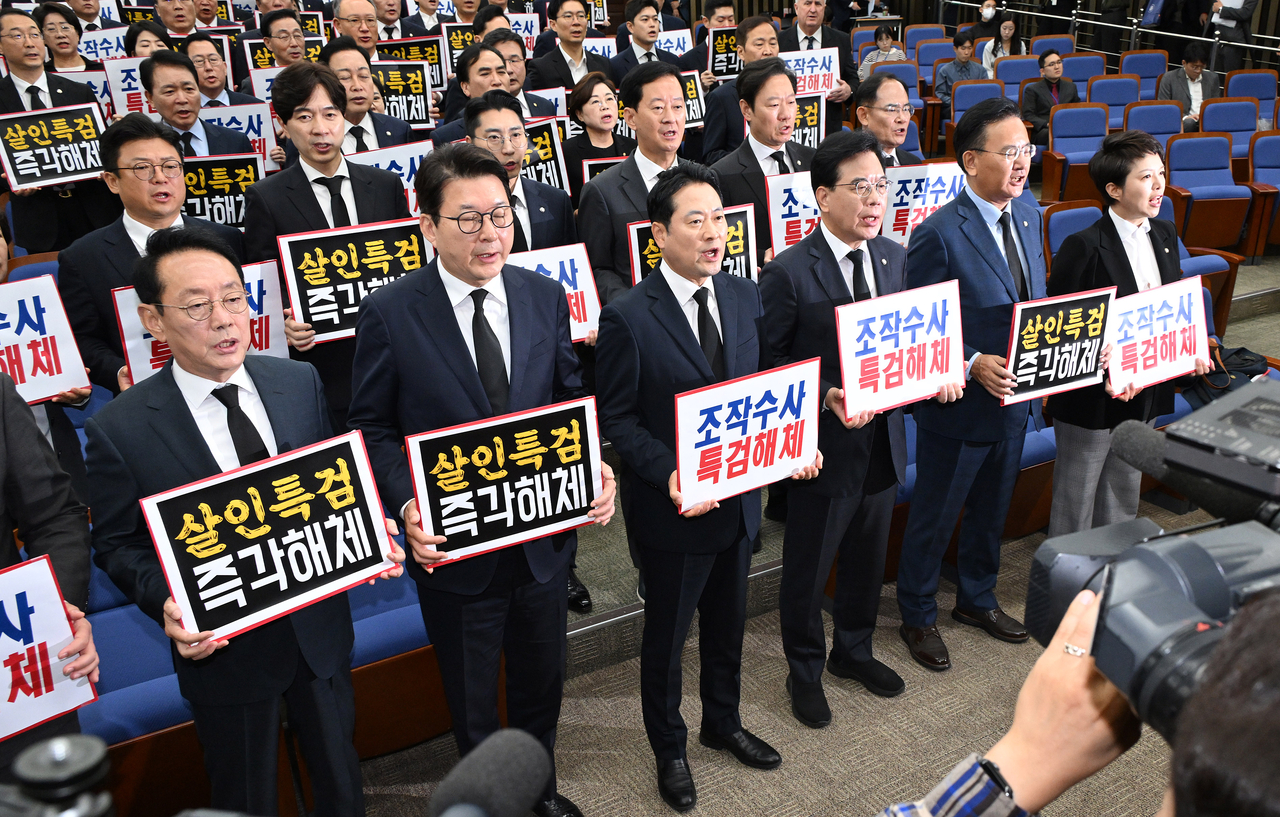 People Power Party leader Rep. Jang Dong-hyeok, floor leader Rep. Song Eon-seog and other PPP lawmakers attend an emergency general meeting at the National Assembly in Yeouido, Seoul, on Oct. 13, wearing mourning attire and holding placards calling for the dissolution of the special counsels investigating Former President Yoon Suk Yeol and others close to him. Lee Sang-sub/The Korea Herald