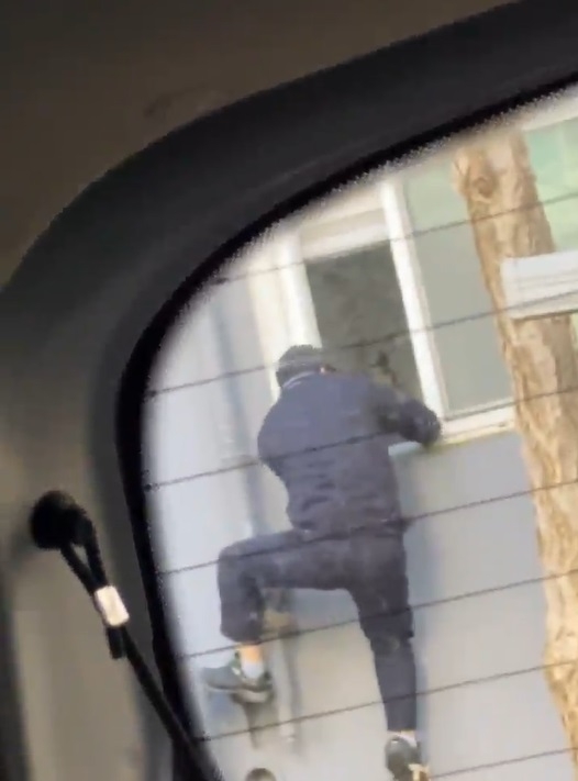 A screenshot from a video shows a man breaking into a first-floor apartment in Siheung, Gyeonggi Province, by climbing through an open window. The footage was taken by a firefighter who was resting in his car parked nearby. (Gyeonggi-do Fire and Disaster Headquarters)