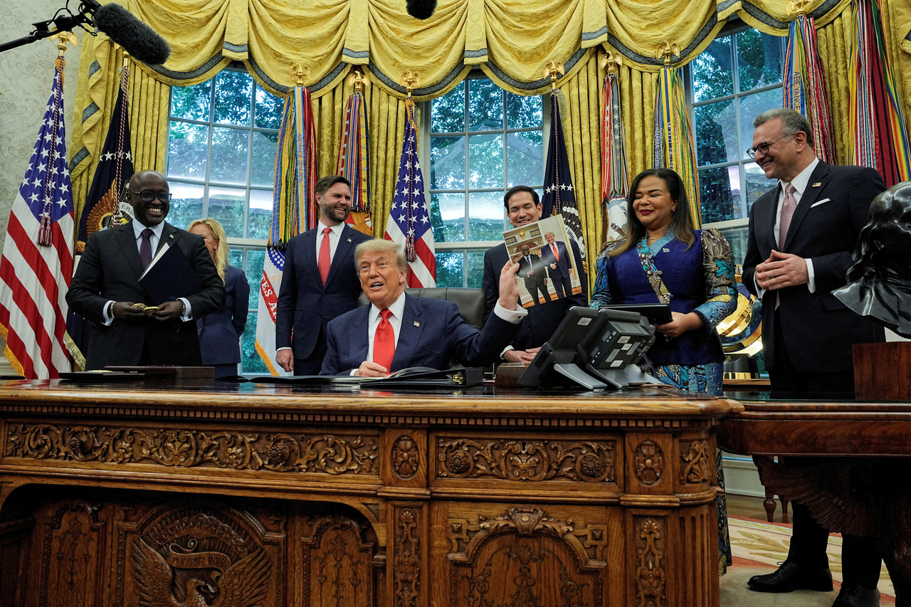 US President Donald Trump holds a picture of himself with Rwanda's Foreign Minister Olivier Nduhungirehe, during a meeting in Washington in June. (Reuters-Yonhap)