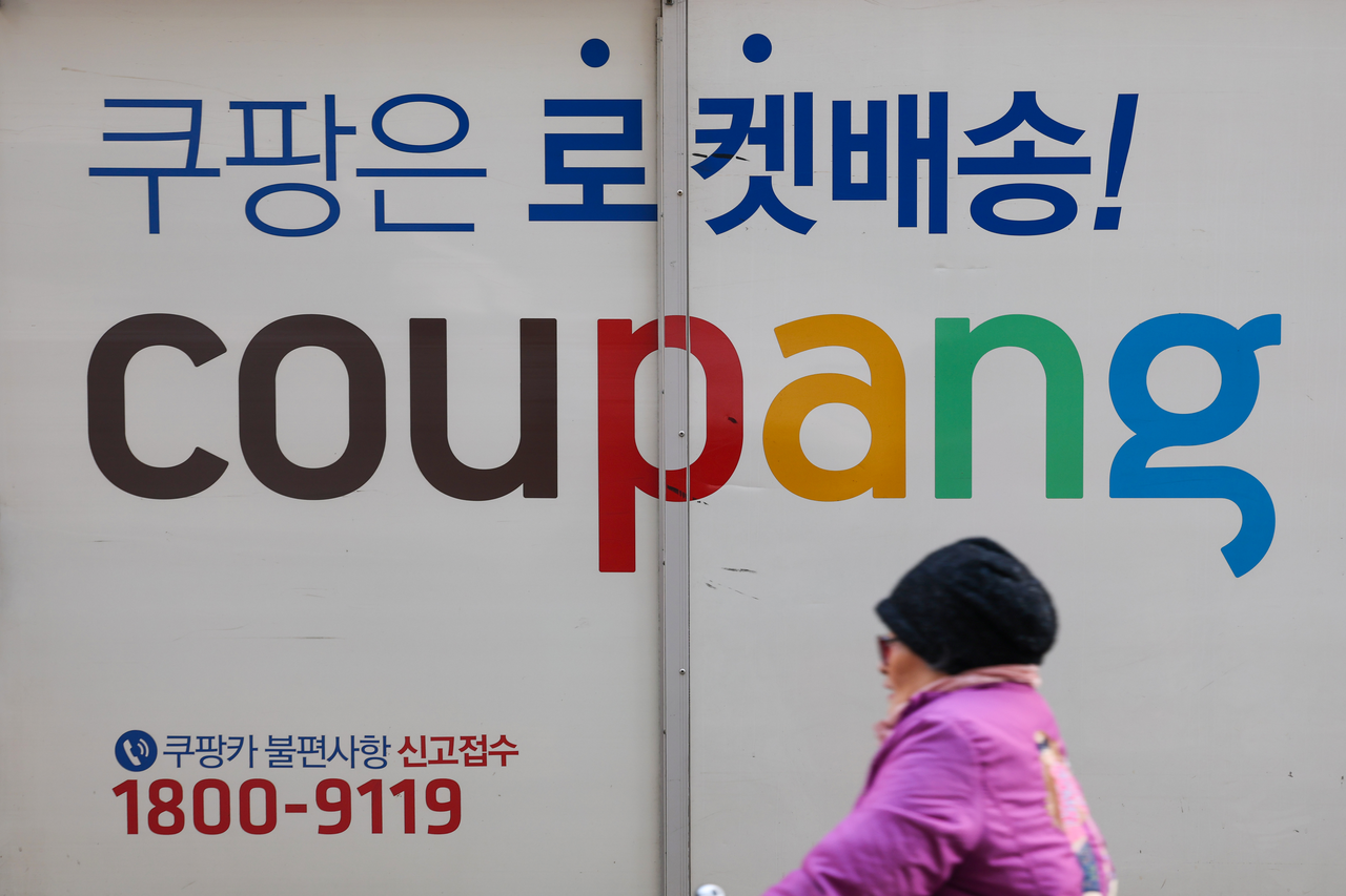 A person passes by a Coupang delivery truck parked in Seoul on Tuesday. (Yonhap)