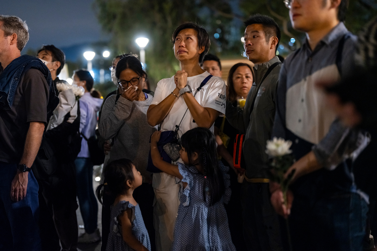 People pray after offering flowers for the victims near the site of a deadly fire, in the Tai Po district, Hong Kong, Tuesday. (AP-Yonhap)