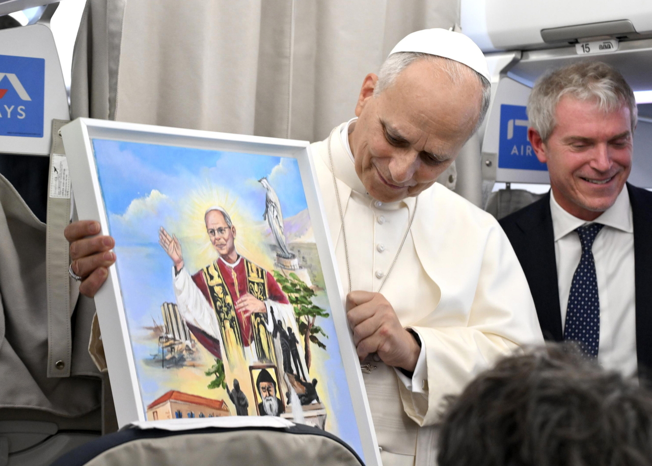 Pope Leo XIV holds a picture as he speaks to journalists aboard a flight to Rome at the end of his apostolic journey, following his departure from Beirut, Lebanon, Tuesday.   (EPA-Yonhap)
