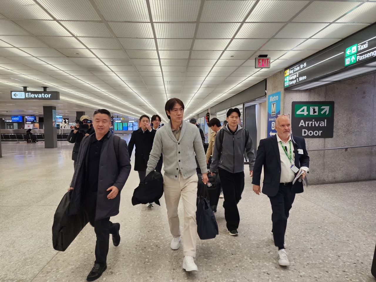 Hong Myung-bo (2nd from L), head coach of the South Korean men's national football team, walks toward an exit at Dulles International Airport, near Washington, D.C., on Wednesday, after arriving in the United States to attend the draw for the 2026 FIFA World Cup. (Yonhap)