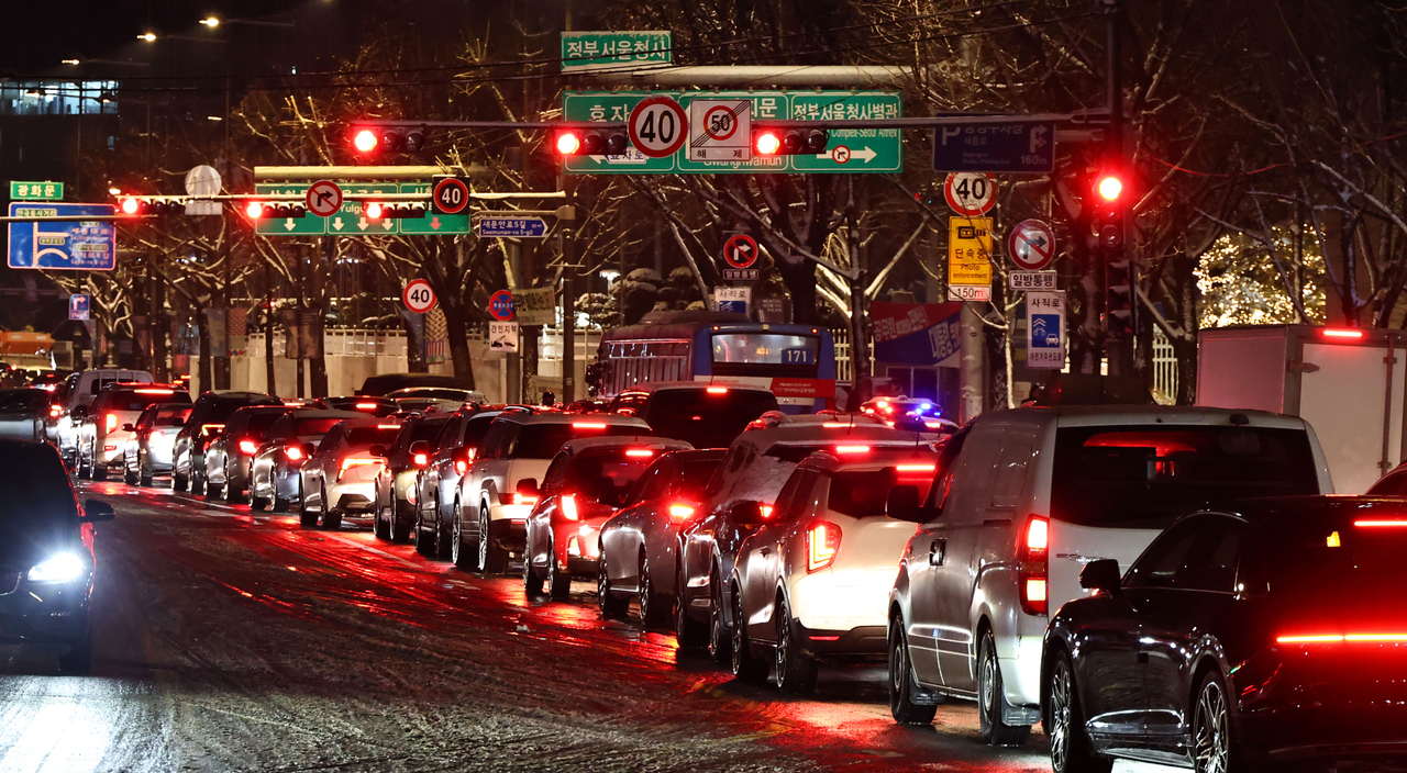 Traffic slows on an icy roadway near Gyeongbokgung Station in Seoul’s Jongno -gu district on Thursday, after the season’s first snowfall. (Yonhap)