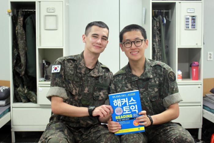 Pvts. Lee Seung-won (left), a South Korean British dual national, and Park Jae-hwan pose for a photo holding a TOEIC preparation book at their barracks in the Army’s 6th Infantry Division in October 2025. (South Korean Army)