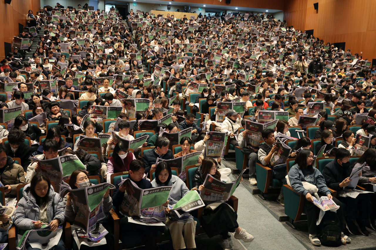 Attendees look up the placement reference charts prepared by Jongno Academy at Sunday's event on college admissions strategies. (Yonhap).