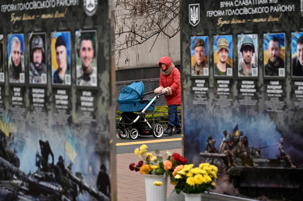 A woman with pram walks past portraits along the Alley of Fallen Heroes in a district of Kyiv, Ukraine, Sunday. (AFP-Yonhap)