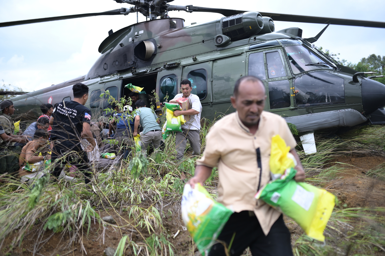 Flood survivors carry relief goods distributed by an Indonesian Air Force helicopter in Aceh, Indonesia, Saturday. (AP-Yonhap)