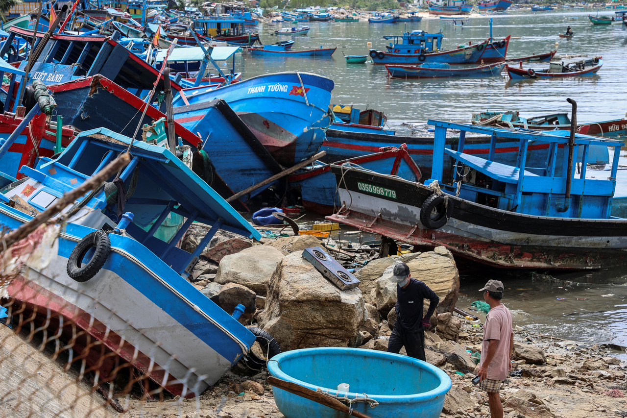 People stand near fishing vessels after Typhoon Kalmaegi hit Dak Lak province, Vietnam, Nov. 8 (Reuters-Yonhap)