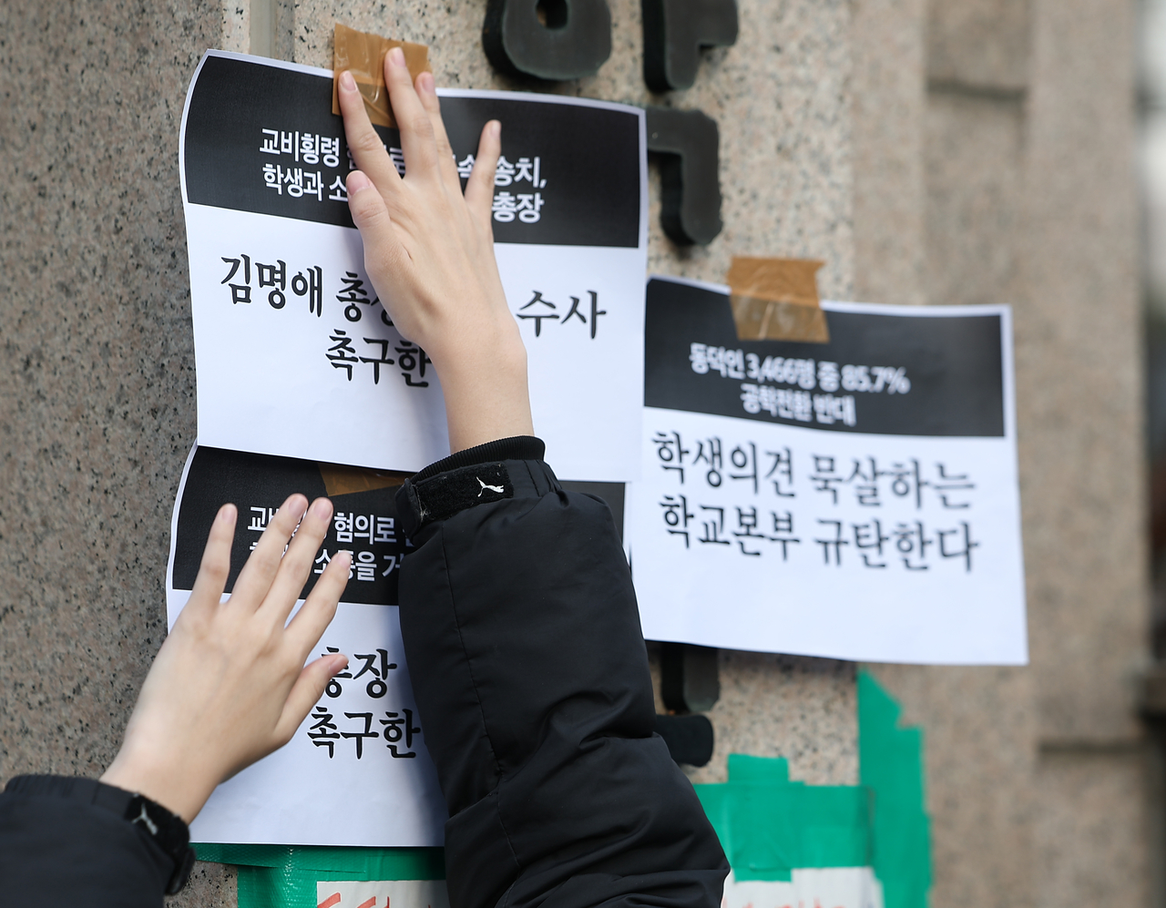 A student at Dongduk Women’s University posts a sign at the campus gate opposing the school’s transition to a coeducational system on Tuesday. (Yonhap)