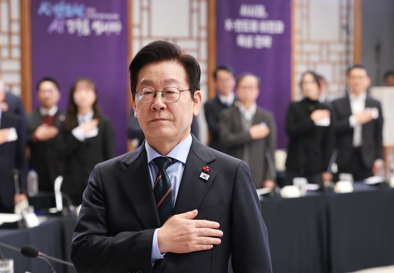 President Lee Jae Myung (center, front) pays respect to the national flag during an event to be briefed about the semiconductor industry blueprint of the government in his office on Wednesday. (Yonhap)