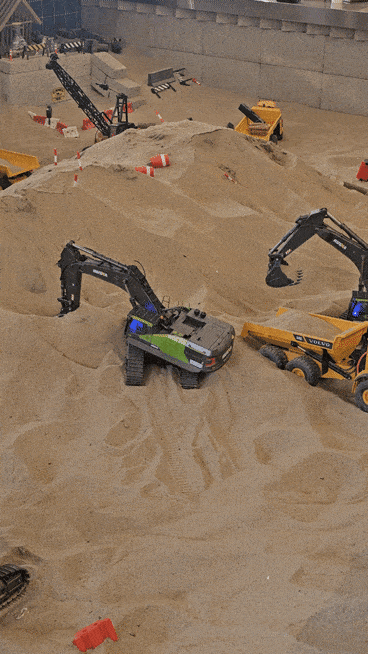 Two remote-controlled mini excavators scoop sand in a large sandbox at Diggerz. (Choi Jae-hee/The Korea Herald)
