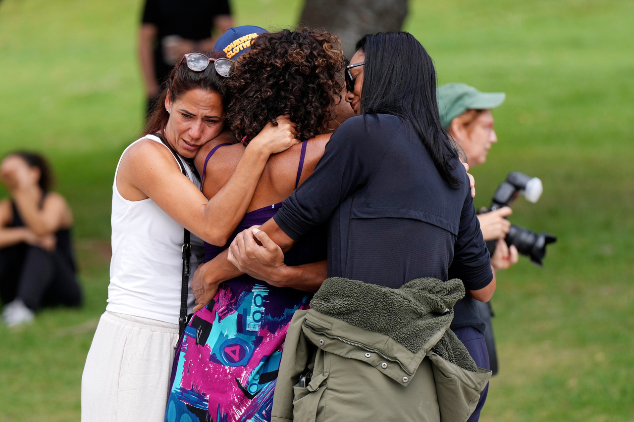 People offer hugs to each other at a flower memorial placed outside Bondi Pavilion at Sydney's Bondi Beach, Monday, a day after a shooting. (AP-Yonap)