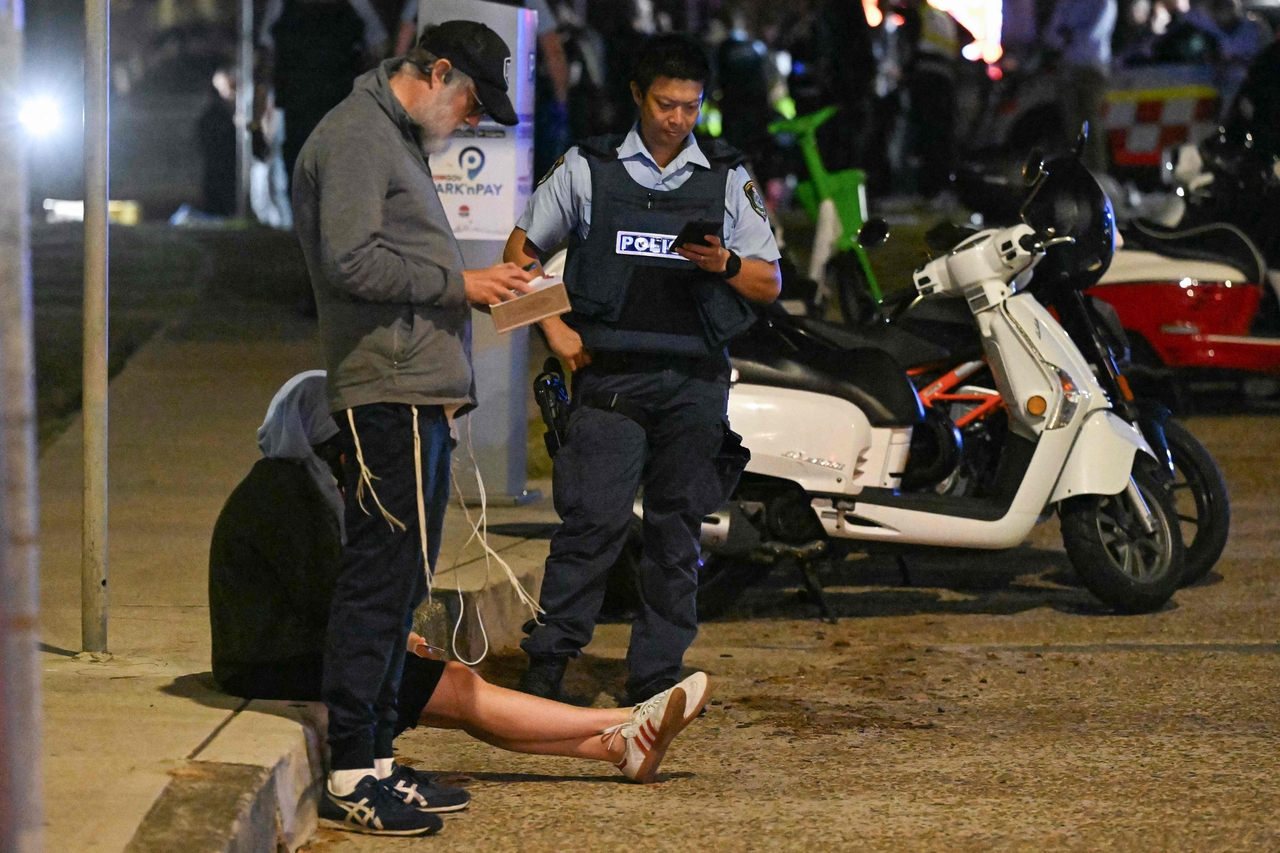 Bystanders stay where police cordon off an area at Bondi Beach after a reported shooting in Sydney, Sunday. (AFP-Yonhap)