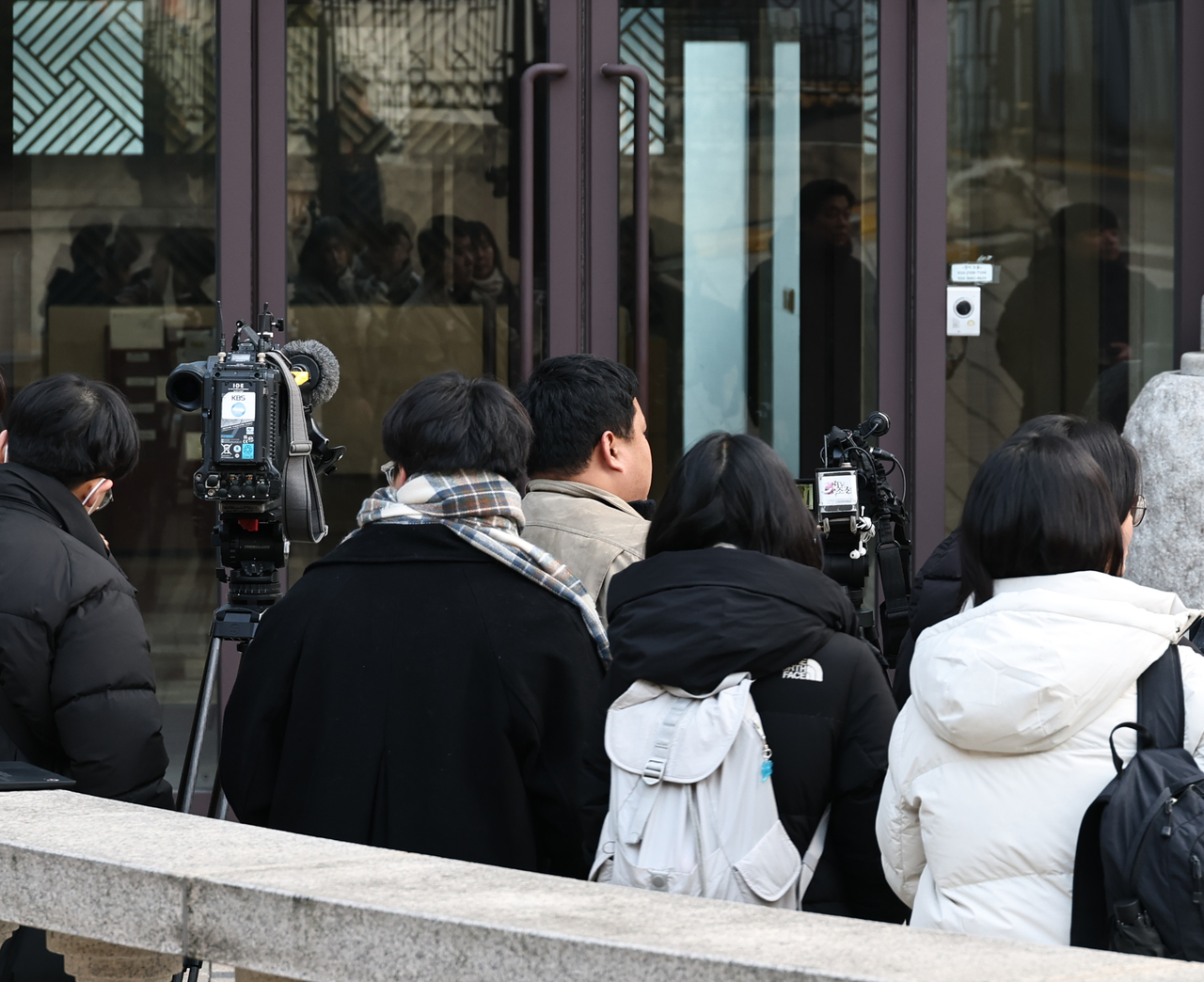 Reporters wait outside the Seoul headquarters of the Unification Church in Yongsan-gu on Monday, as police conduct raids on multiple church offices and locations as part of an investigation into allegations that political figures received money or valuables from the group. (Yonhap)
