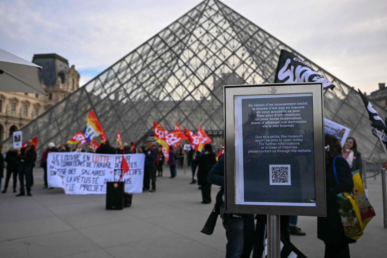 A notice informs of the closure of the Louvre Museum as members of the French CGT union protest outside the entrance in Paris, Monday. (AFP-Yonhap)