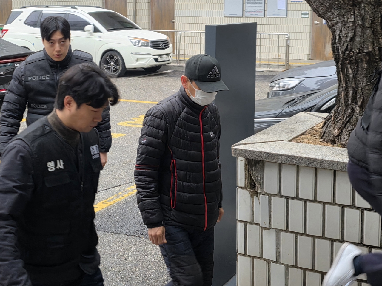 The suspect (front right), who is accused of dousing his Thai wife's face with boiling water, arrives at the Uijeongbu District Court on Tuesday for his arrest warrant hearing. (Yonhap)