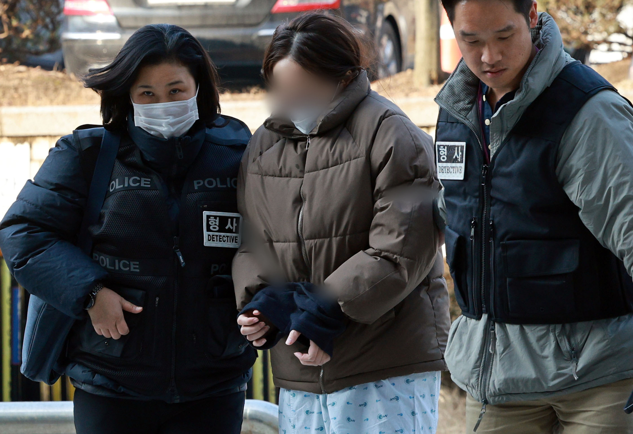 The suspect in a murder by child abuse case (center) enters the Seoul Central District Court for the hearing on her arrest warrant Wednesday. (Yonhap)