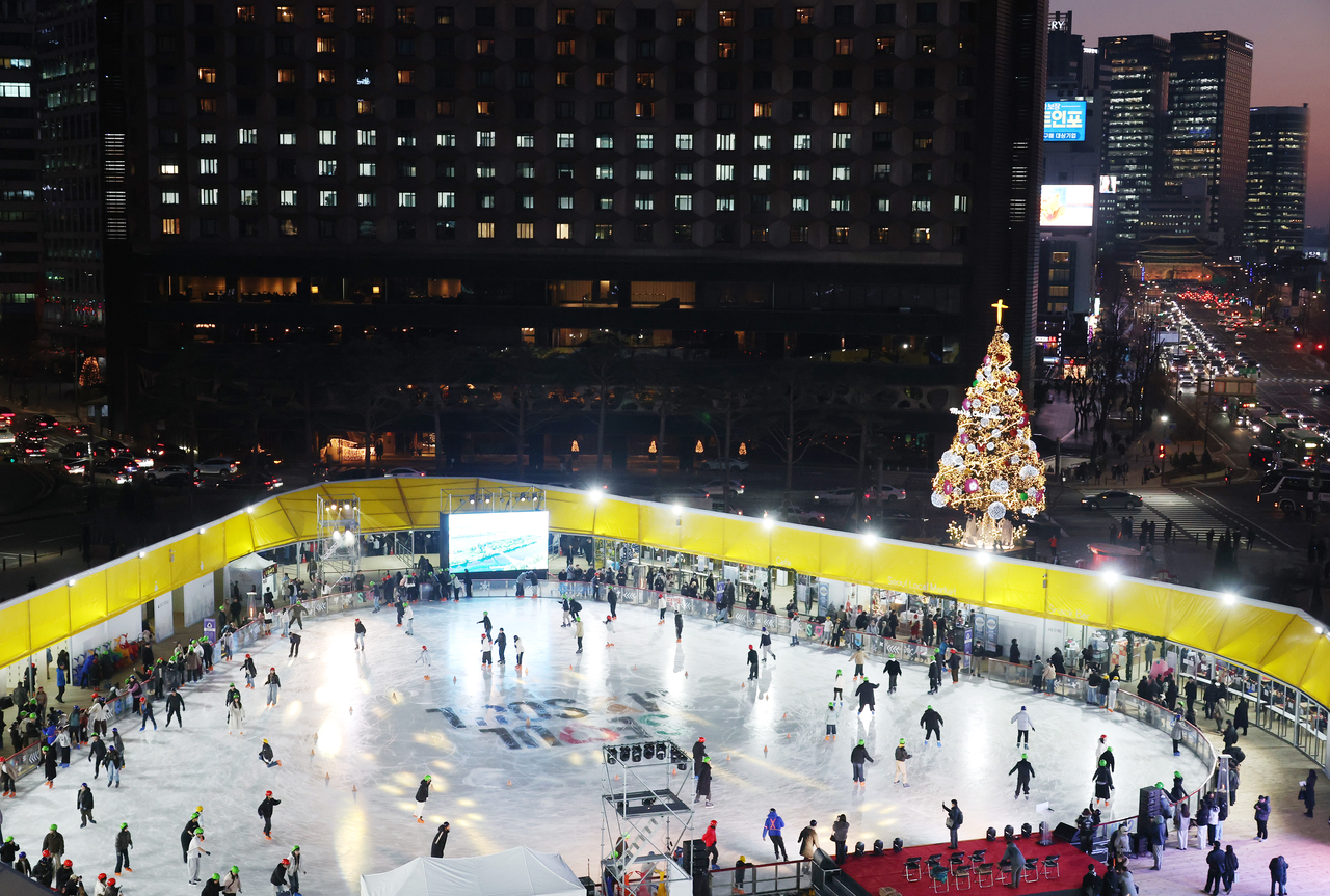 Skaters enjoy the ice at Seoul Plaza on Friday, as the rink’s diamond-shaped ring glows in warm yellow light. (Yonhap)