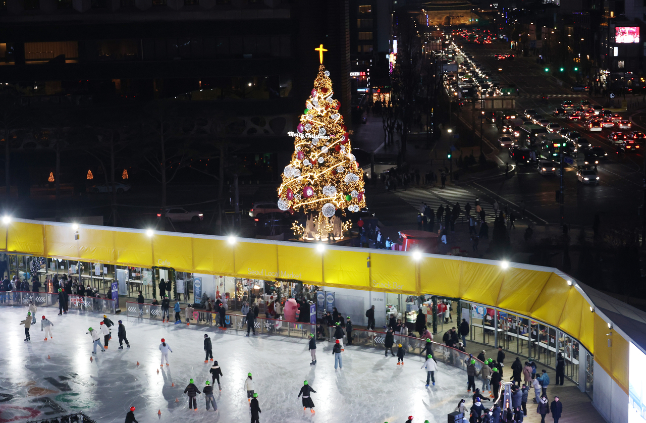 Skaters enjoy the ice at Seoul Plaza on Friday, with a giant Christmas tree standing near the rink. (Yonhap)