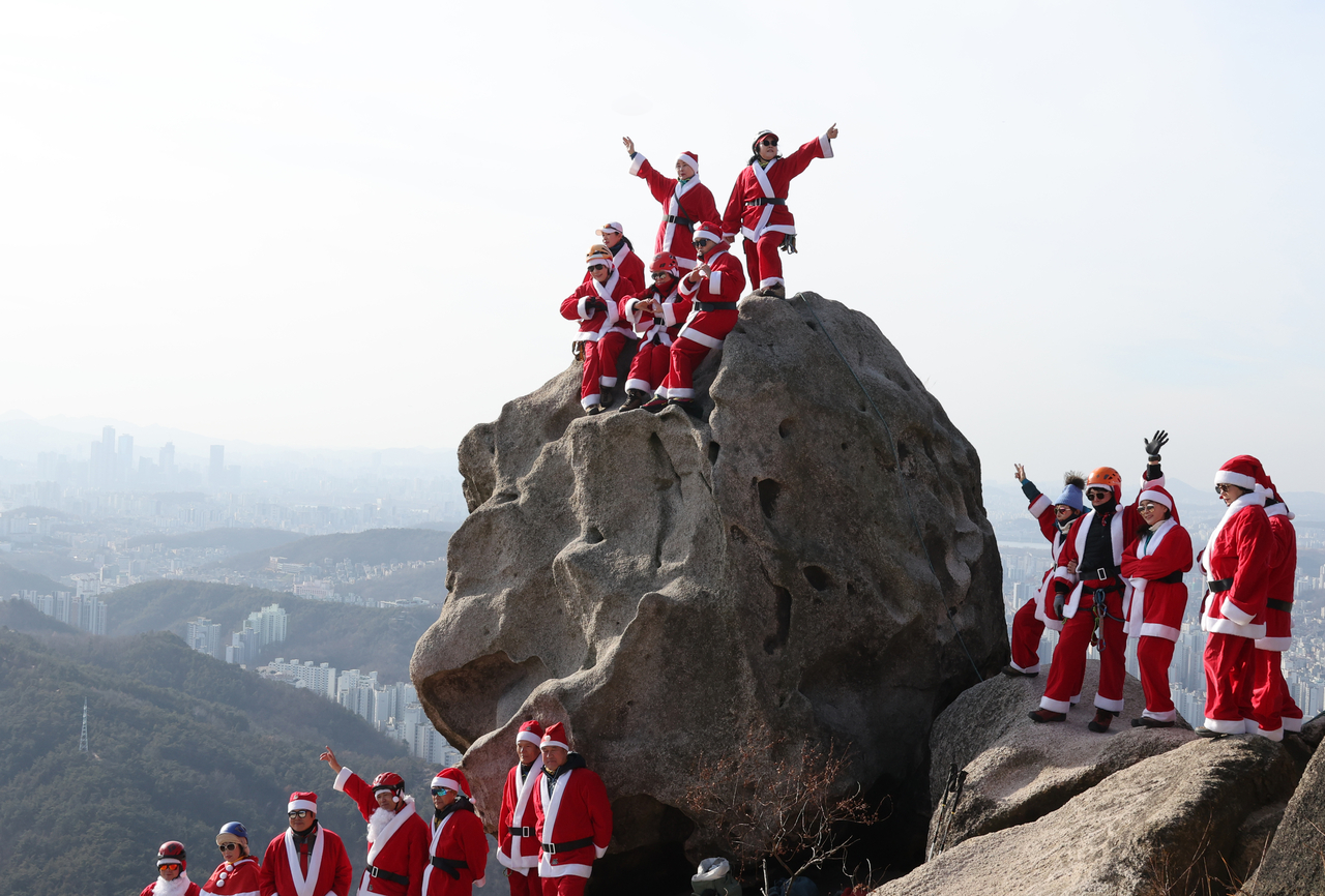 Dressed as Santa Claus, Korea National Park Service rangers and members of a hiking club scale the Jokduribong Peak in Bukhansan, Seoul, on Sunday to pray for safety in 2026, ahead of Christmas. (Yonhap)