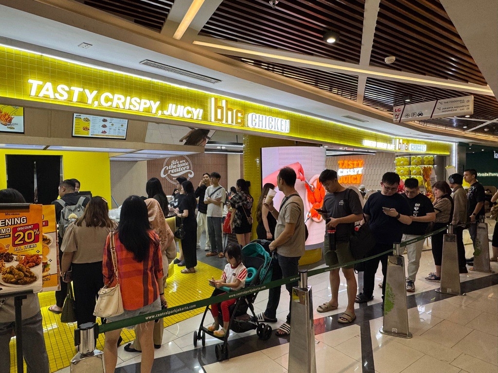 Customers line up to order and pick up chicken at the first Indonesian outlet of BHC, a fried chicken franchise under Dining Brands Group, at Neo Soho Mall in central Jakarta on Monday. The store features an interior with the brand’s signature yellow and localized menu options combining chicken, rice and beverages. “We aim to deliver the unique taste and experience of K-chicken as a representative Korean brand,” said the head of the group’s global business division, Nam Hwa-yeon. (Dining Brands Group)
