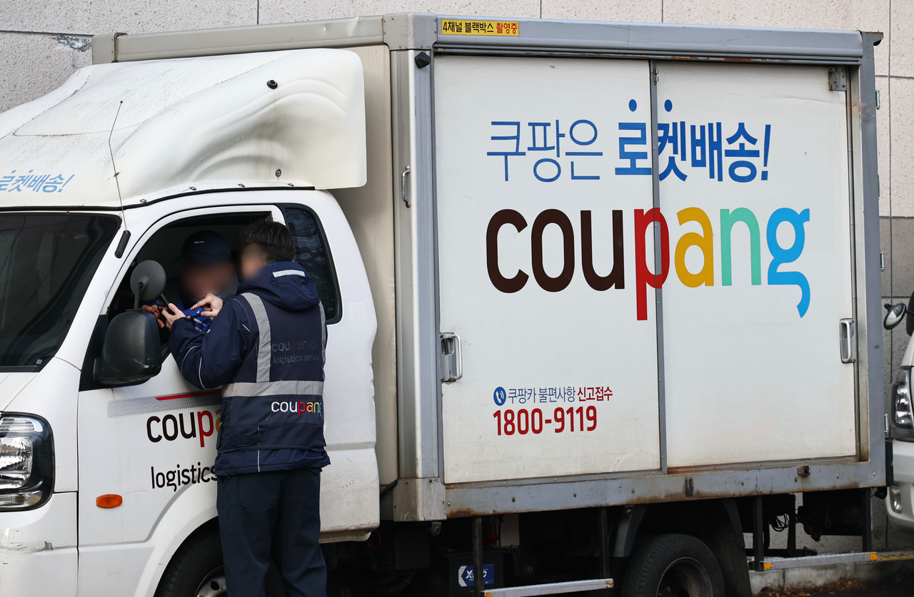 A parcel delivery driver speaks to a co-worker at a Coupang delivery truck in Seoul on Wednesday. (Yonhap)
