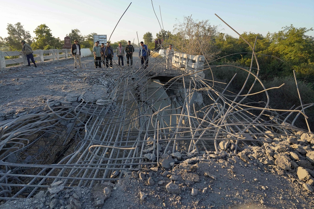 People look at a damaged bridge after Thailand carried out air strikes in an area between Cambodia's Oddar Meanchey and Siem Reap provinces on Saturday. (AFP)