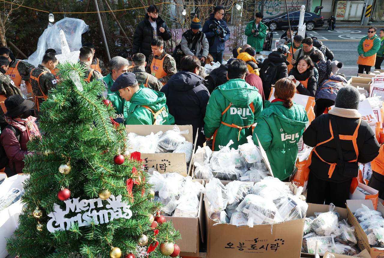 Volunteers from the Babfor Sharing Movement headquarters distribute food and daily necessities to people in need on a street in Dongdaemun-gu, Seoul, on Wednesday. (Yonhap)