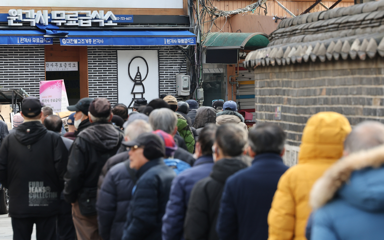 Long lines of older people stretch out in front of a free meal center inside Tapgol Park, operated by Wongaksa under the Jogye Order of Korean Buddhism, on Wednesday morning. (Yonhap)