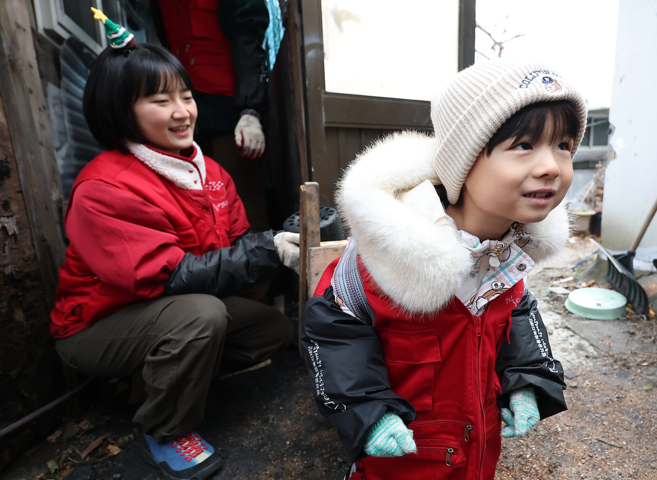 An 8-year-old boy carries a coal briquette on a wooden carrier strapped to his back in a multihousing neighborhood in Jeongneung-dong, Seongbuk-gu, Seoul, on Wednesday. (Yonhap)