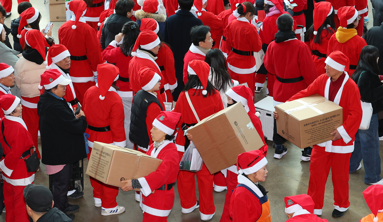 Volunteers participating in a Santa Claus Festival held in Incheon on Christmas Day are seen setting off with gift boxes to be delivered to underprivileged communities. (Yonhap)