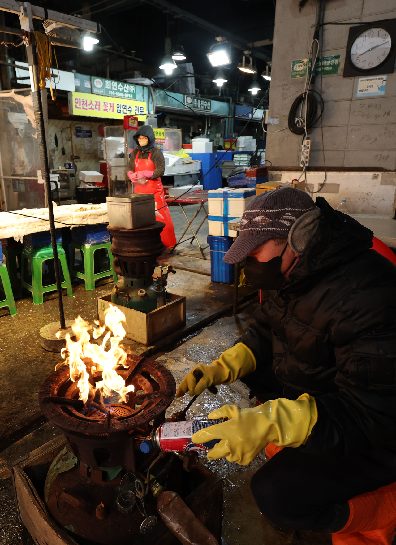 A merchant at the Garak Agricultural and Marine Products Wholesale Market in Songpa district, Seoul, keeps warm next to a gas burner on Friday. (Yonhap)