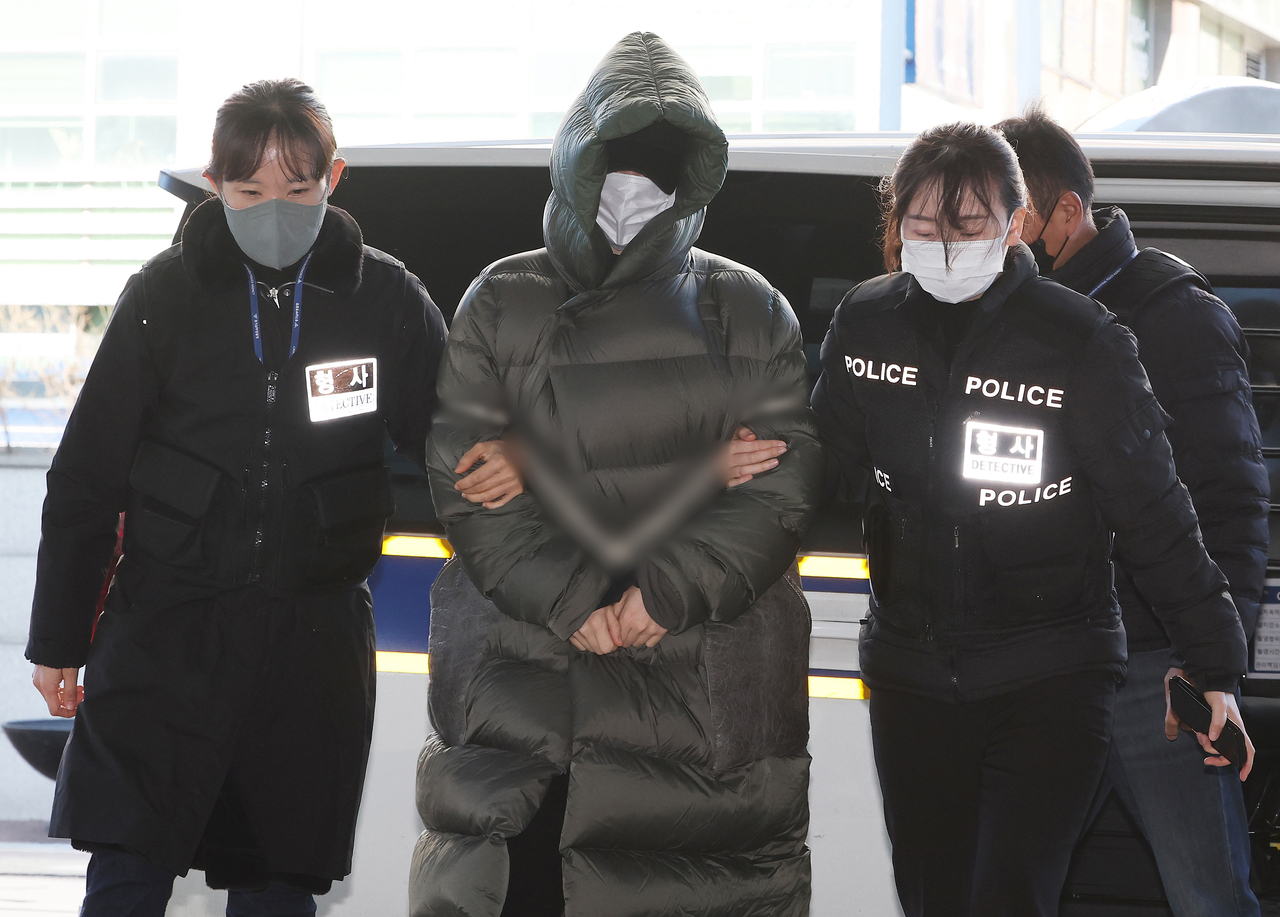 Hwang Ha-na (center) is escorted by police officers as she arrives at the Anyang Branch of the Suwon District Court for a hearing on her arrest warrant on Friday. (Yonhap)