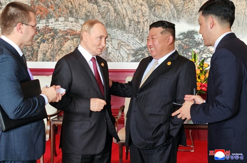 This Korean Central News Agency photo on Sept. 4 shows North Korean leader Kim Jong-un (2nd from R) talking to Russian President Vladimir Putin during their summit talks in Beijing the previous day. (Yonhap)
