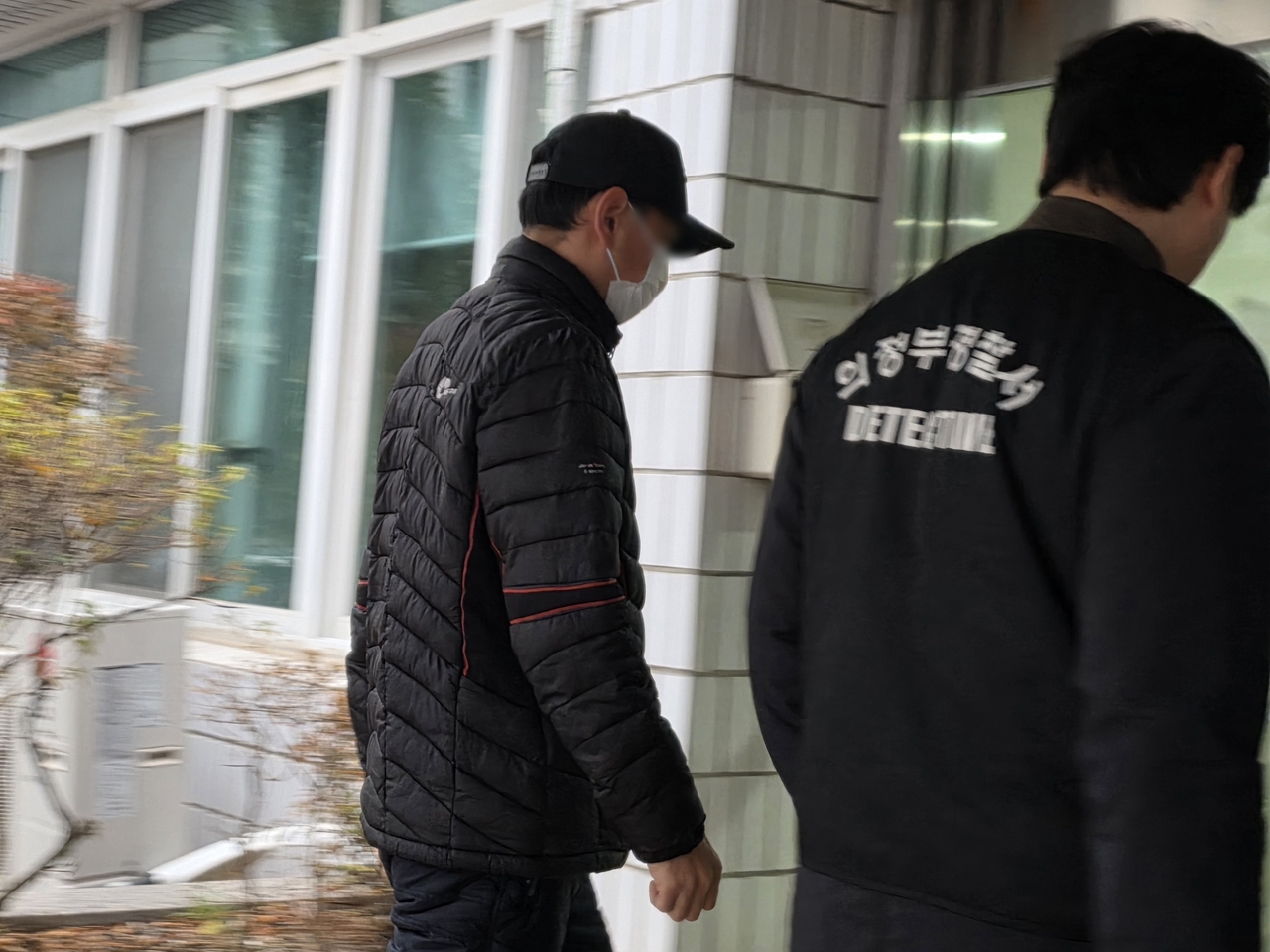 The suspect (left), who is accused of dousing his Thai wife's face with boiling water, arrives at the Uijeongbu District Court on Tuesday for his arrest warrant hearing. (Yonhap)