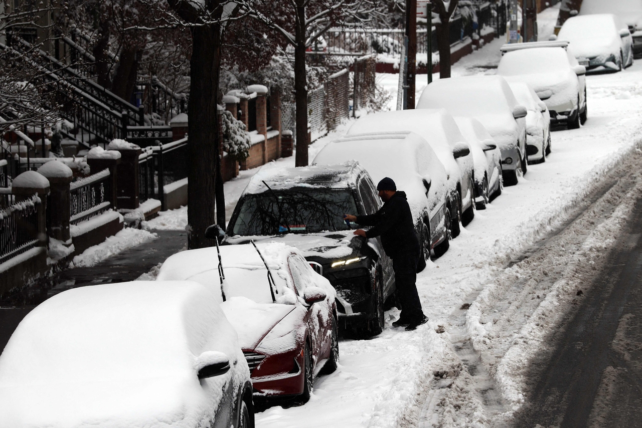 A man cleans off his car of snow in Brooklyn after an overnight storm in New York, Saturday. (AFP-Yonhap)