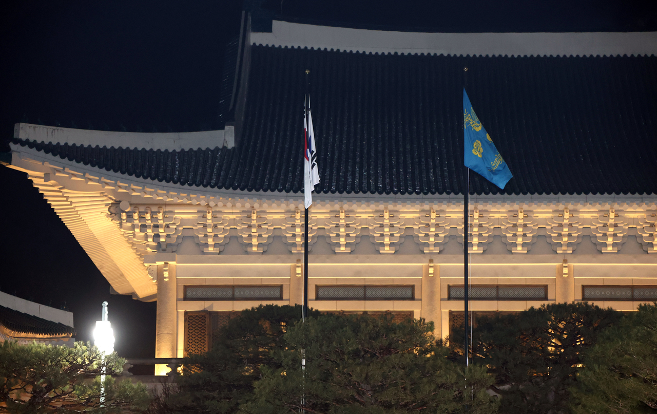 Presidential officials raise a presidential flag bearing two phoenixes at the main building of Cheong Wa Dae on  Monday. (Yonhap)