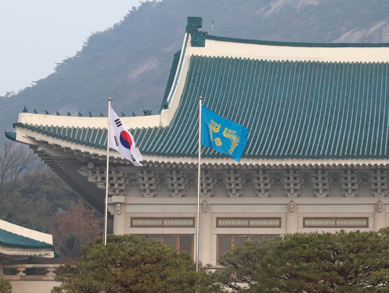 The phoenix flag (right), a symbol of the presidency, flutters alongside South Korea’s national flag in front of Cheong Wa Dae on Monday, marking its return as the presidential office for the first time in 1,330 days since former President Moon Jae-in last commuted there on his final day in office on May 9, 2022. (Yonhap)