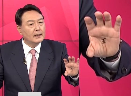 This screenshot from YouTube shows the Chinese character for "king" drawn on then-presidential candidate Yoon Suk Yeol's palm during a 2021 televised debate held ahead of the 2022 presidential election.  (YouTube)