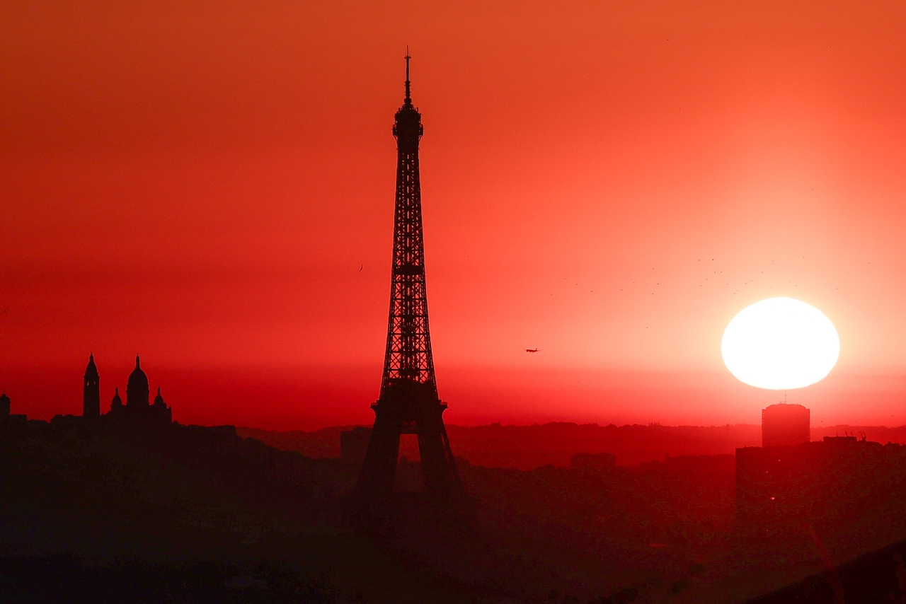 The sun rises by the Eiffel Tower in Paris in July. (AFP-Yonhap)