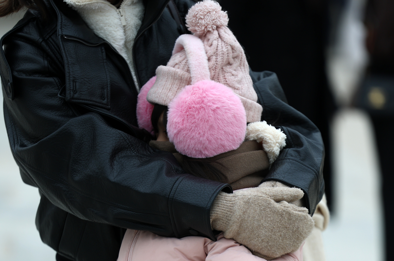 A tourist shields a child from the cold wind in Gwanghwamun, Seoul on Saturday, as freezing temperatures gripped the capital.  (Yonhap)