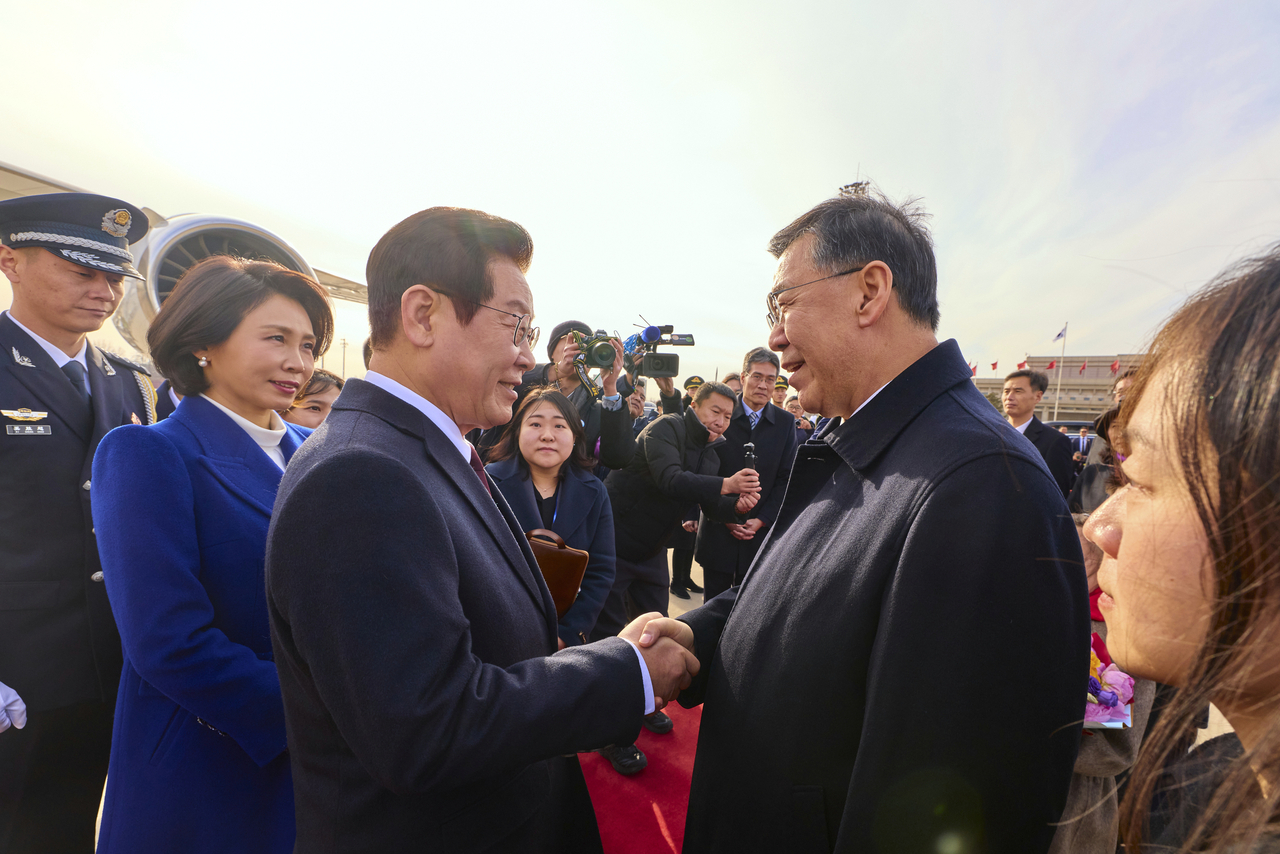 President Lee Jae Myung is welcomed by Yin Hejun, China’s minister of science and technology, upon his arrival at Beijing Capital International Airport on Sunday. (Pool photo via Yonhap)