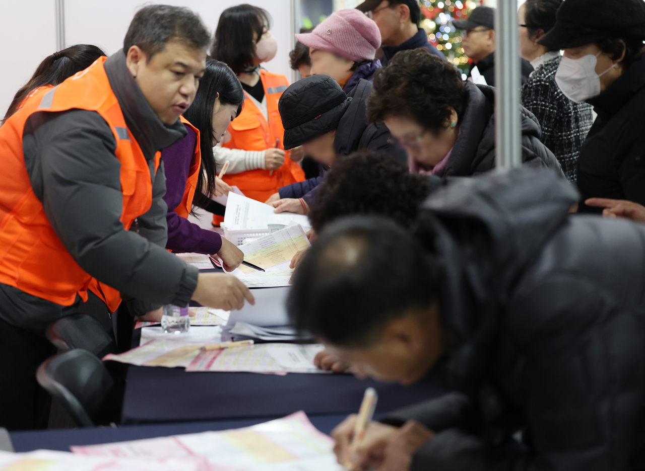 Senior jobseekers fill out paperwork at a senior job fair at held at the Mapo District Office in Seoul on Dec. 10, 2025. (Yonhap)