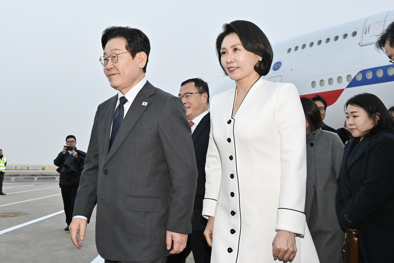 President Lee Jae Myung (left) and first lady Kim Hea Kyung arrive at Shanghai Pudong International Airport in Shanghai on Tuesday. (Yonhap)