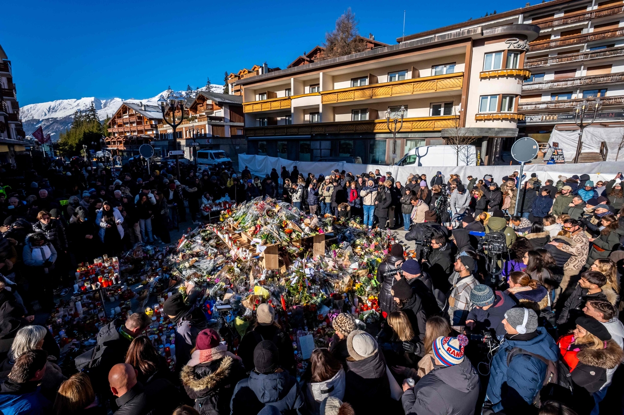 People gather around a makeshift memorial to pay their respects by laying flowers, candles and messages near the Constellation bar, Sunday, in Crans-Montana in honour of the victims of the fire that ripped through the venue in the luxury Alpine ski resort on New Year's Eve.  (AFP-Yonhap)