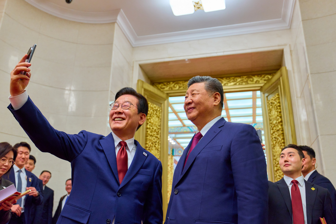 President Lee Jae Myung (L) takes a selfie with Chinese President Xi Jinping by using a Xiaomi smartphone following a state dinner in Beijing on Jan. 5, 2026. The smartphone was gifted to Lee by Xi during their first summit talks in Gyeongju, South Korea, in November 2025. (Pool photo) (Yonhap)